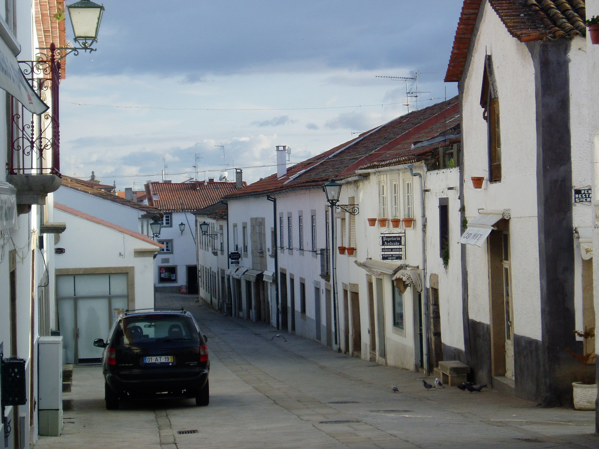 the car is driving down the narrow, old town street