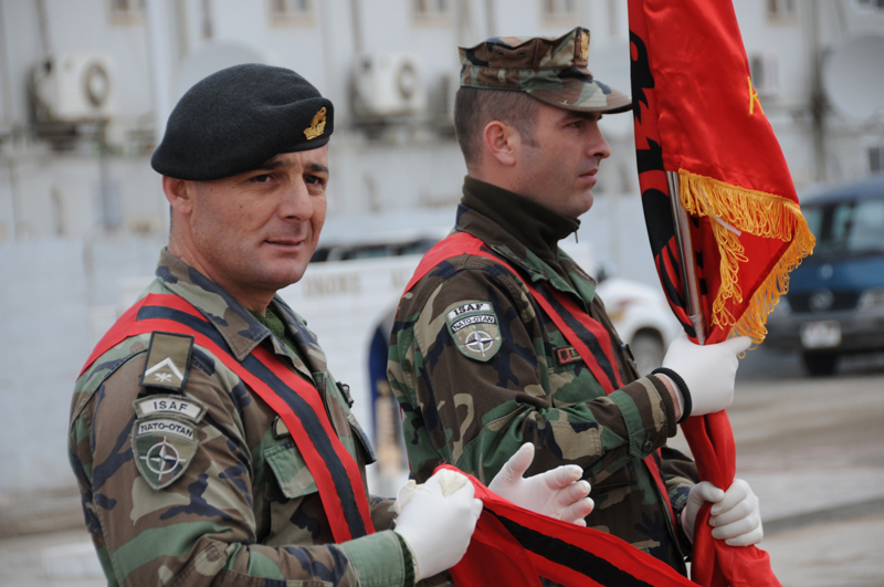 two men in camouflage with flags in a street