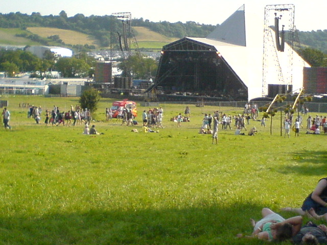 many people in a grassy area watching soing with some type of musical equipment