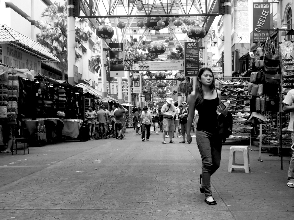 a woman walking down the middle of an aisle of stores