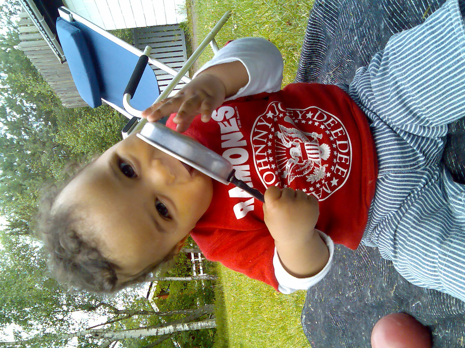  in red shirt and a baseball hat holding up a little blue chair