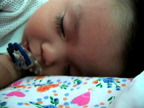 a little  sleeping with a pacifier on its mouth