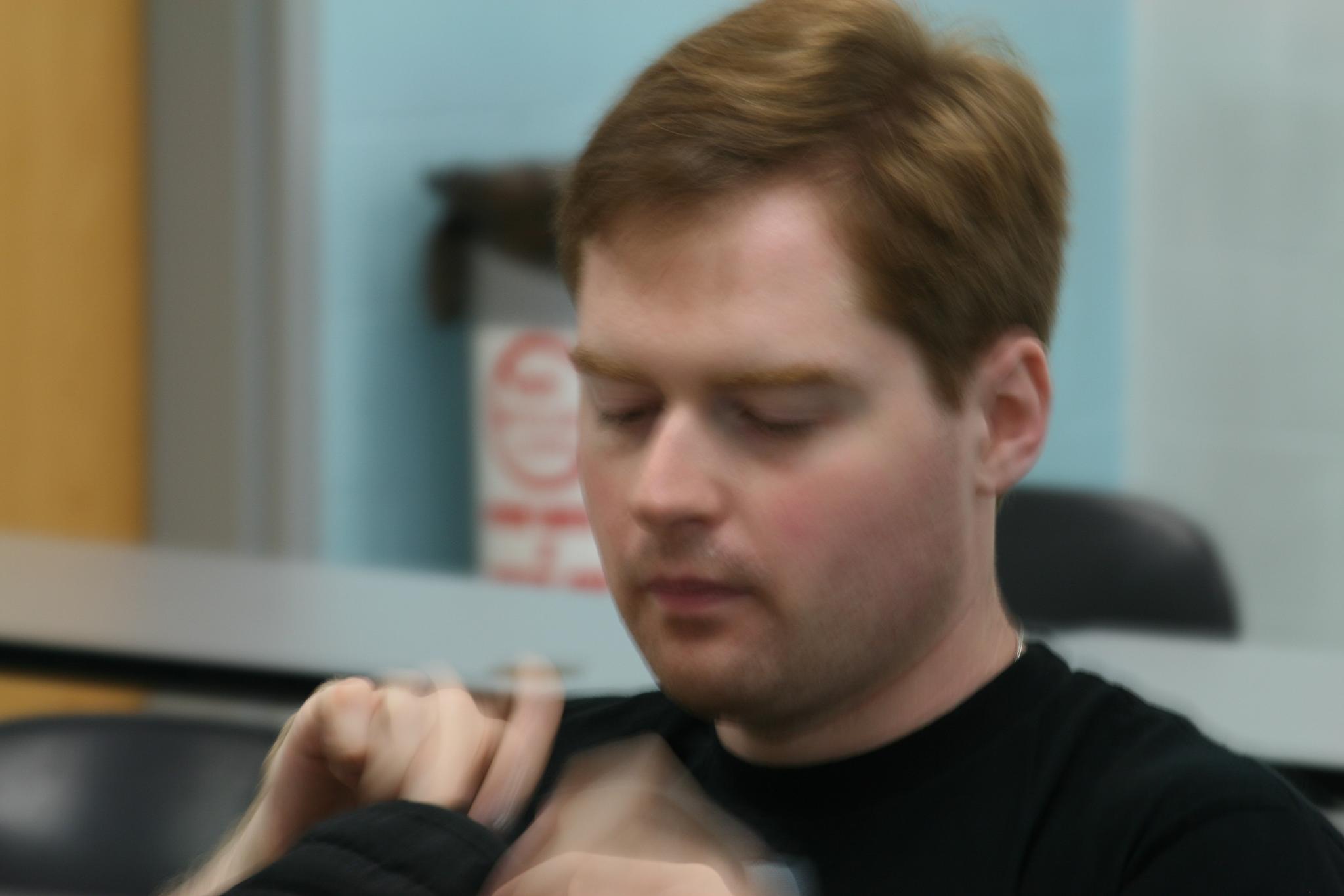 a man wearing black shirt fixing his tie