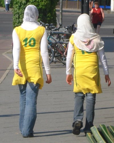 two people wearing yellow and white are walking down the street