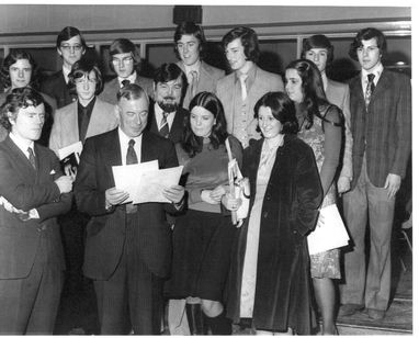 many people with papers posing together in front of a group