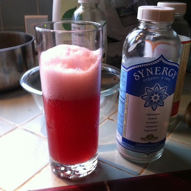 a red drink is in front of a pitcher and some bottles