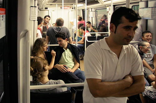 man standing next to woman on train, crowded subway car