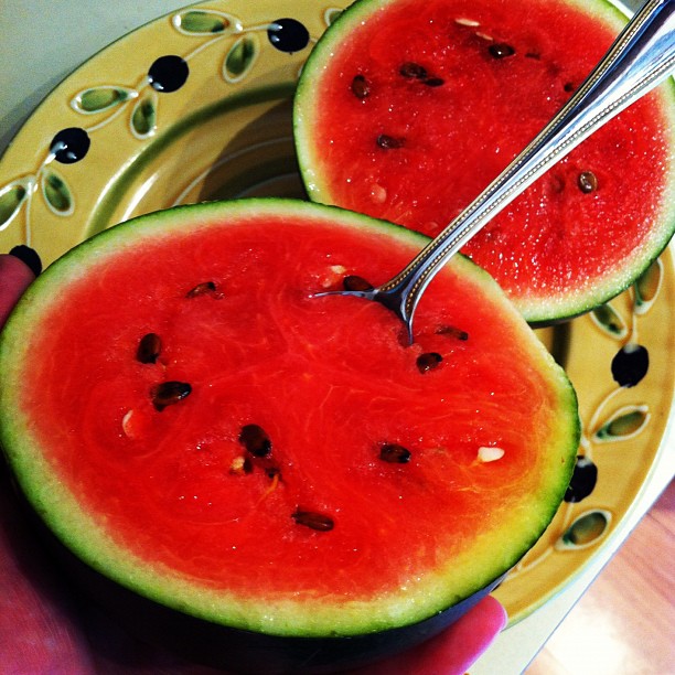 a person is  a slice of watermelon with a knife and fork