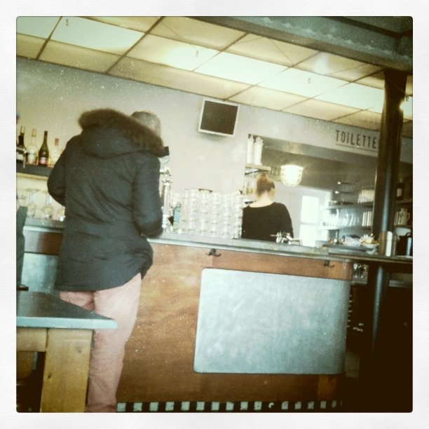 a woman in black coat standing by the bar