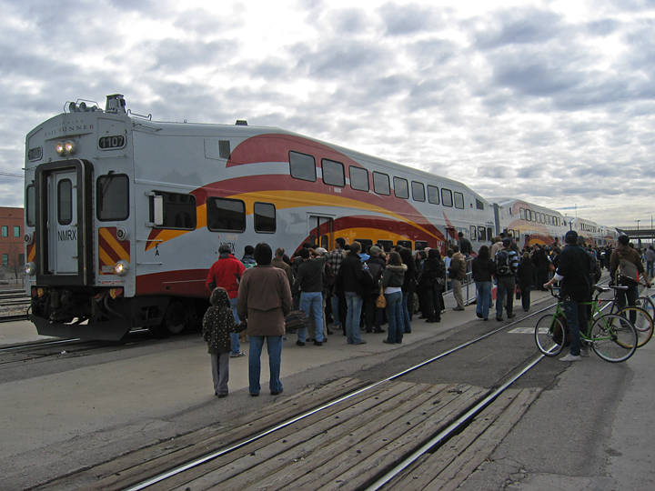 people on the rails waiting to board the commuter train