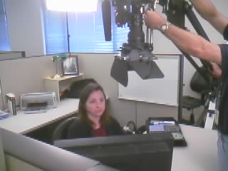 a woman is filming another person behind a computer