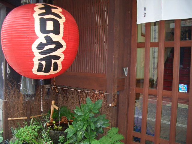 red chinese lantern with lettering above a potted plant
