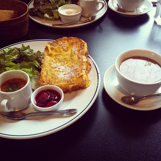 two breakfast plates with food on top of it and cups of tea