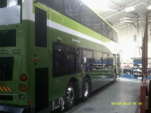 a green bus that is in a garage