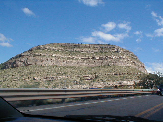 view from inside a car showing large rock formation on the side