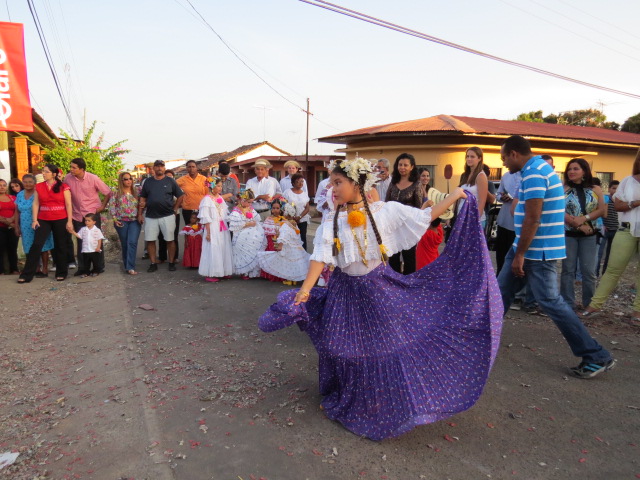 a woman in a purple dress and others dancing on the street