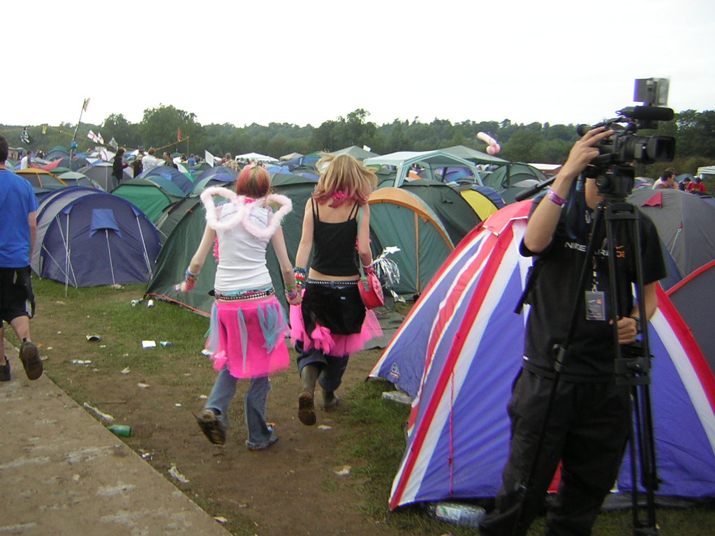 a woman taking a po near tents as two others walk away