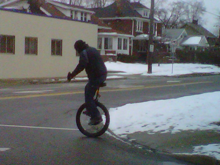 there is a man that is riding an unicycle in the street