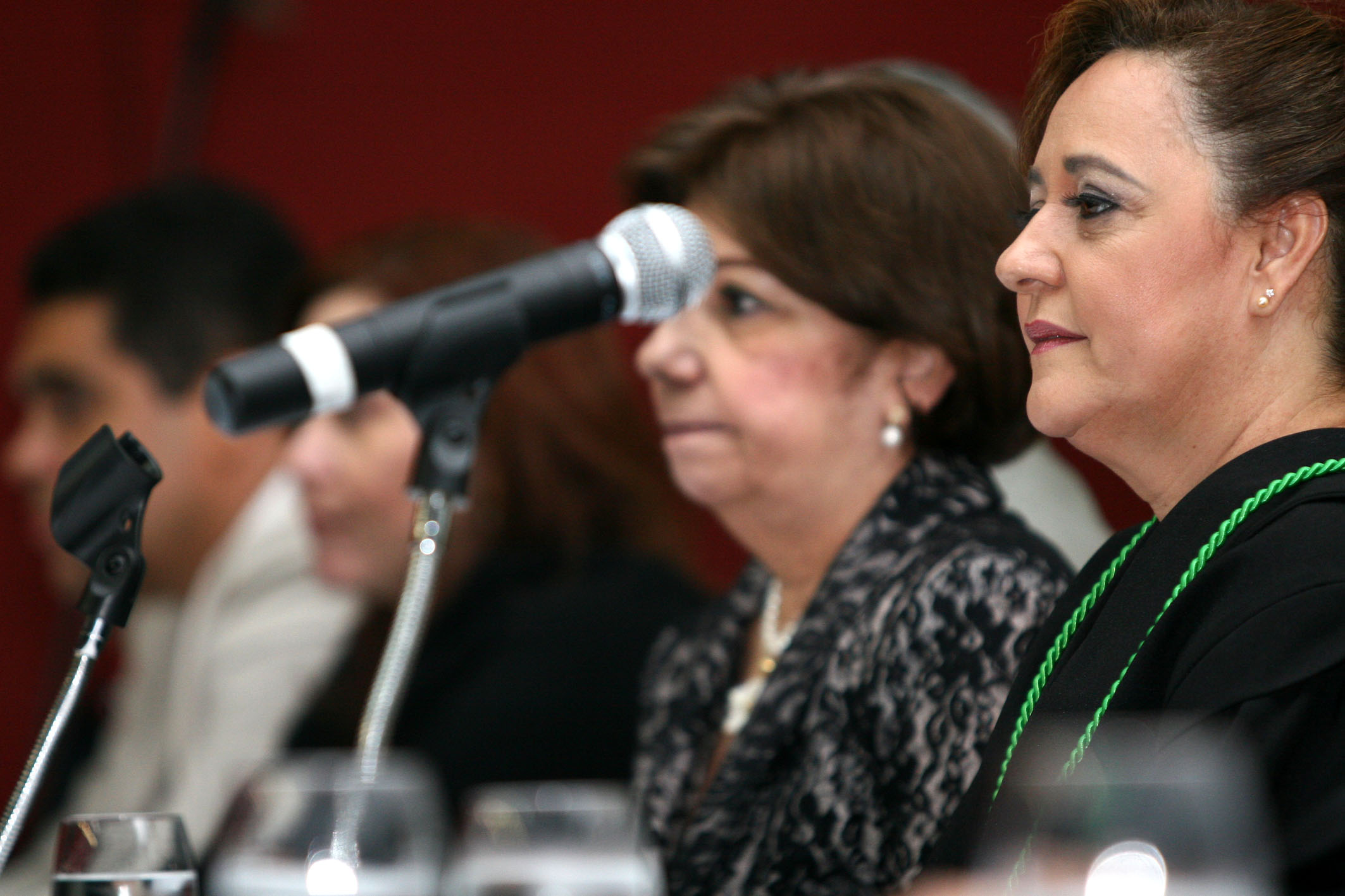 two women sitting at tables with microphones in front of them