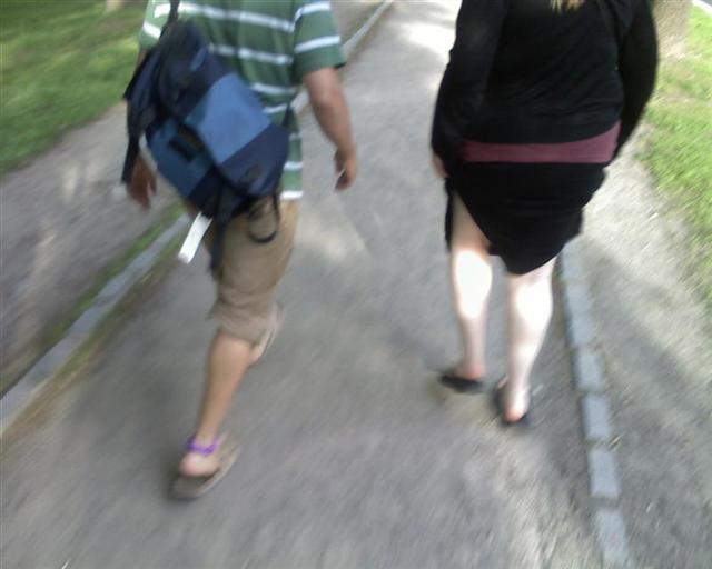 two people walking down a street together and one is holding a blue backpack