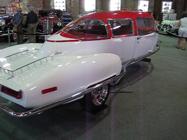 some people looking at a classic car displayed