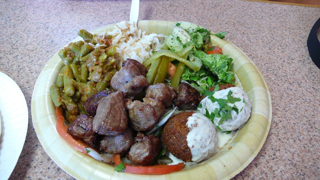 a paper plate containing meat, vegetables and potatoes