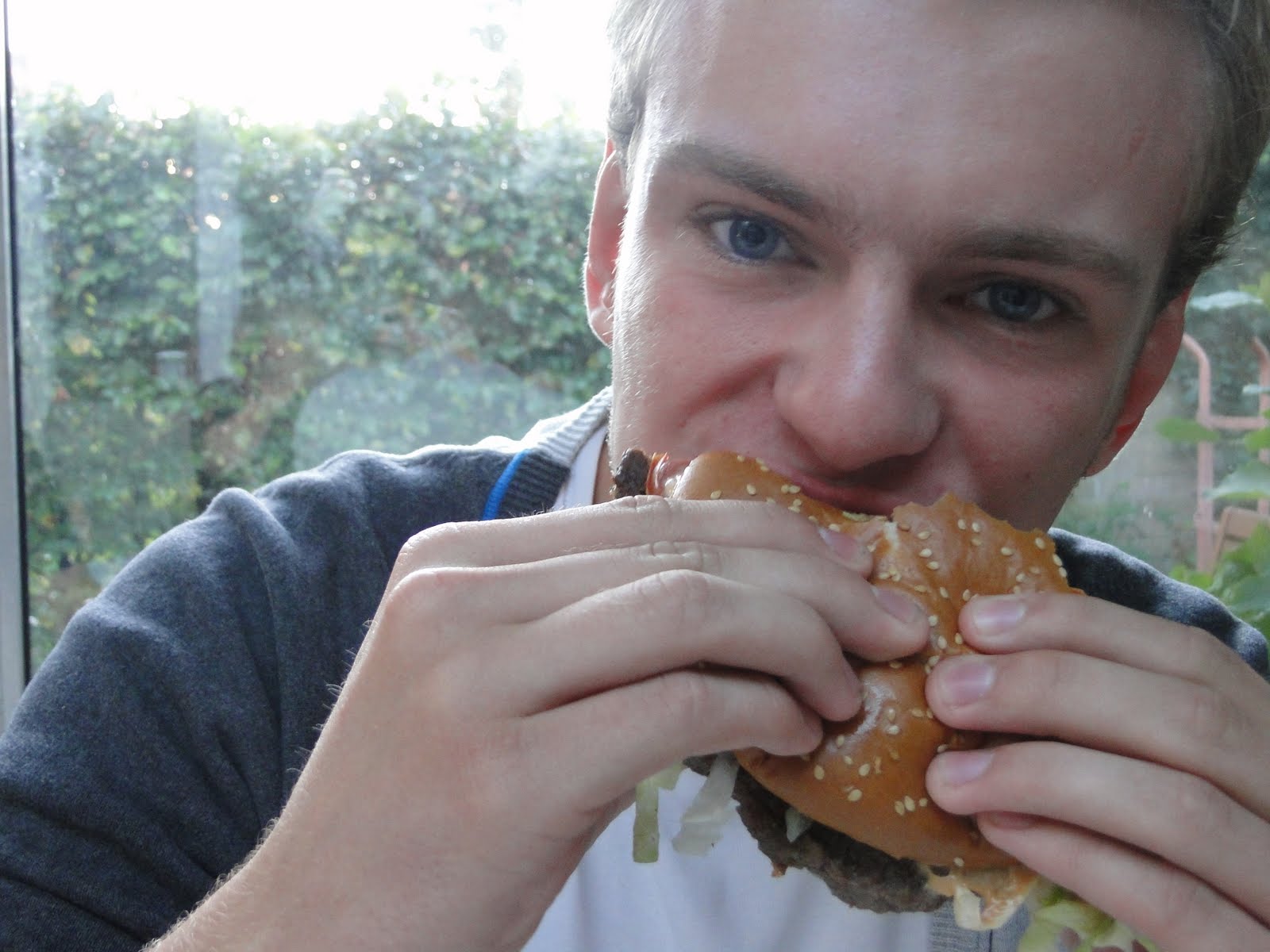 a man eating a  dog while sitting down