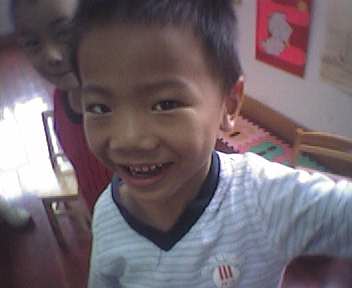 a boy in a white striped shirt smiling at the camera