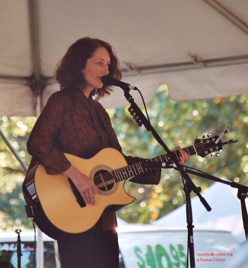 a woman singing into microphone and playing guitar
