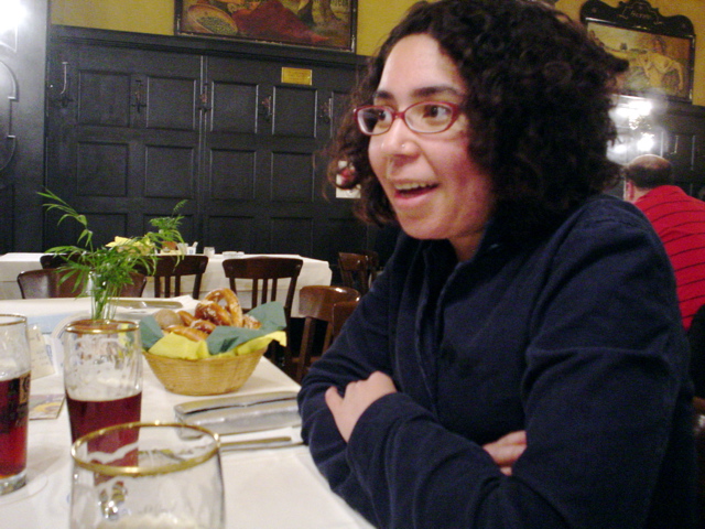 a woman with glasses sitting at a table in front of drinks