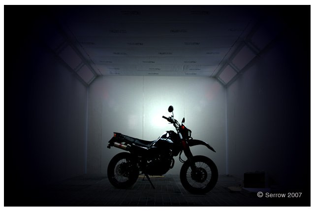 a motorcycle sits in the dark against a light