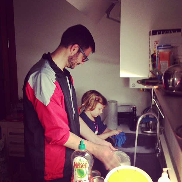 a man and a girl in the kitchen by the sink