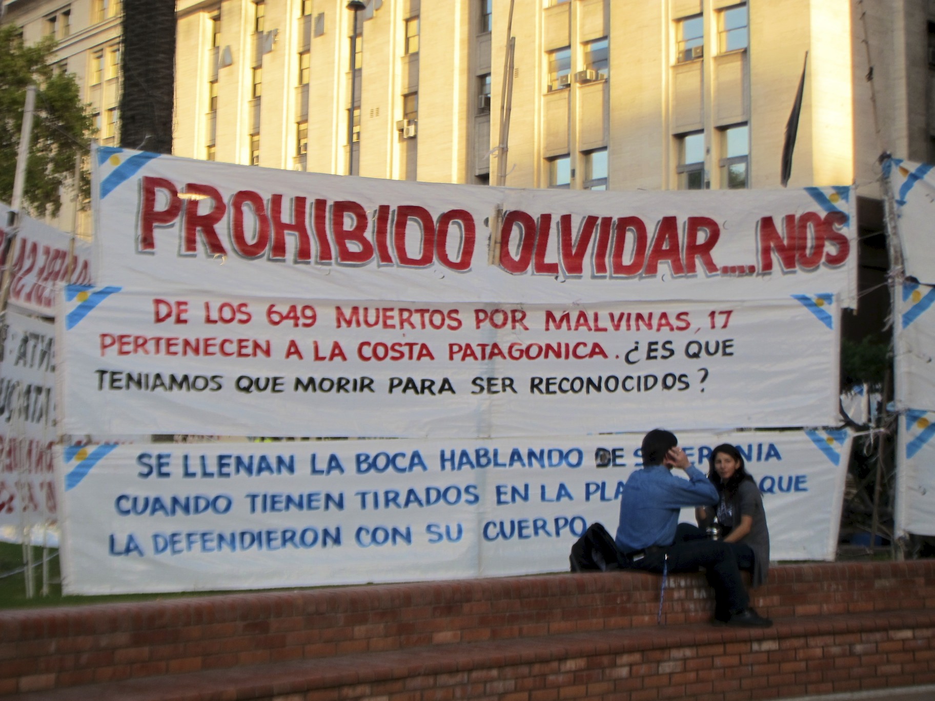 the people are sitting on the steps by the billboard