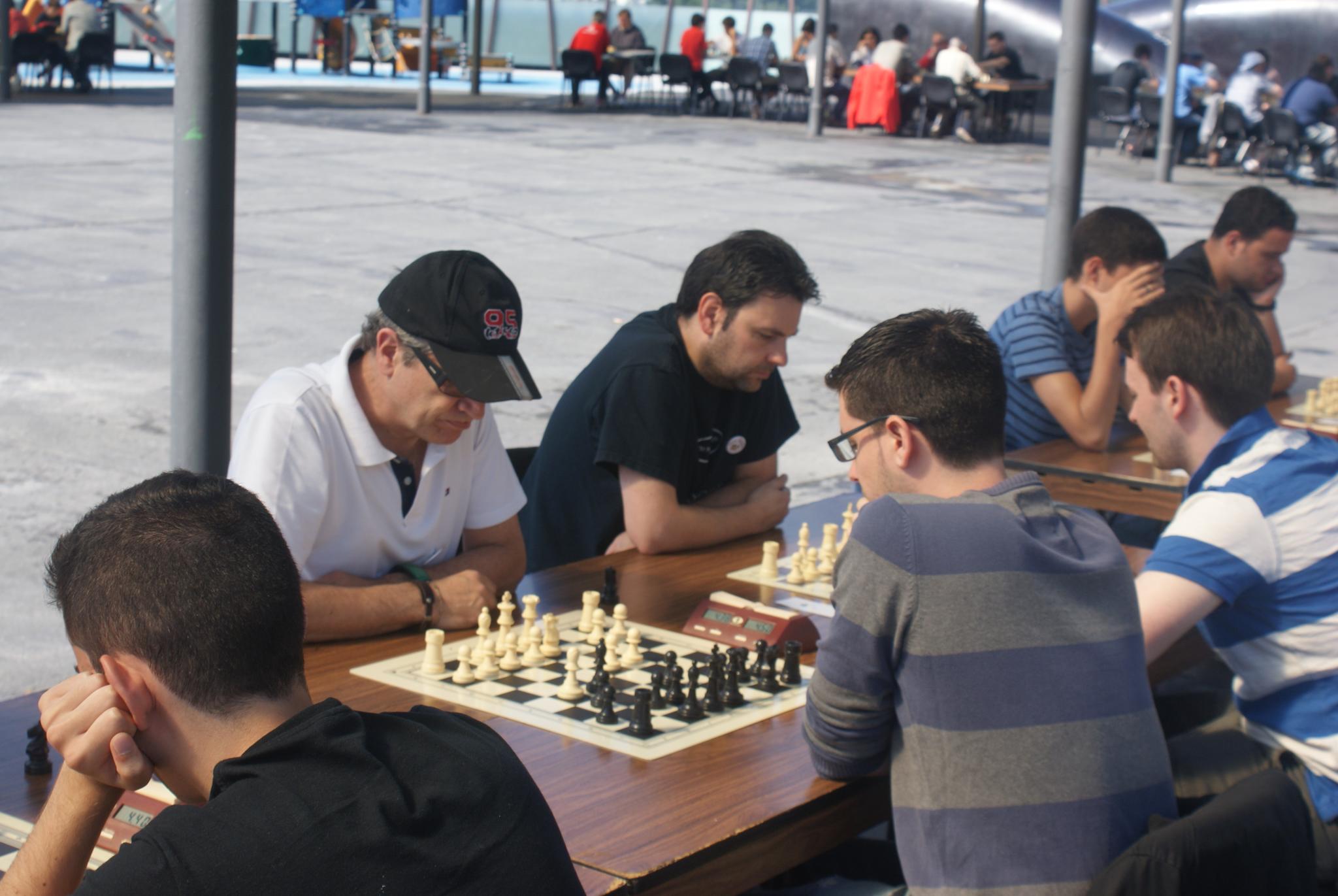 several people are sitting around a table with chess