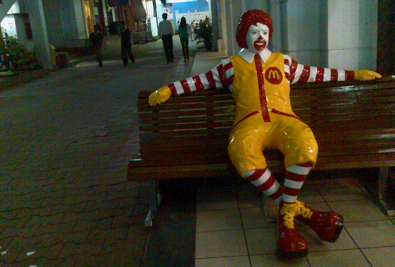 a large ronald mcdonald statue sitting on top of a bench