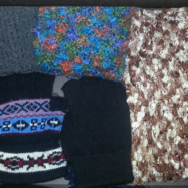 several different knitted clothing sitting on a bed