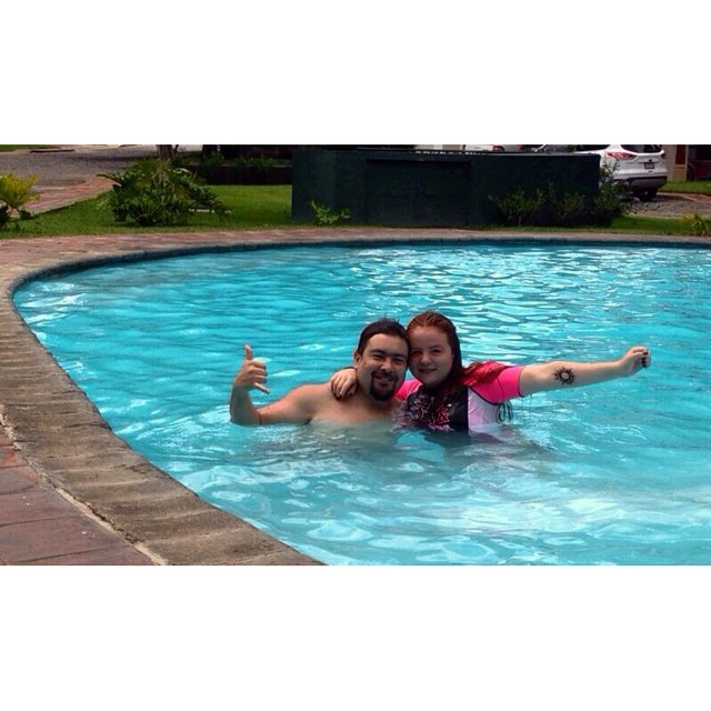 a woman and man pose for the camera in a pool