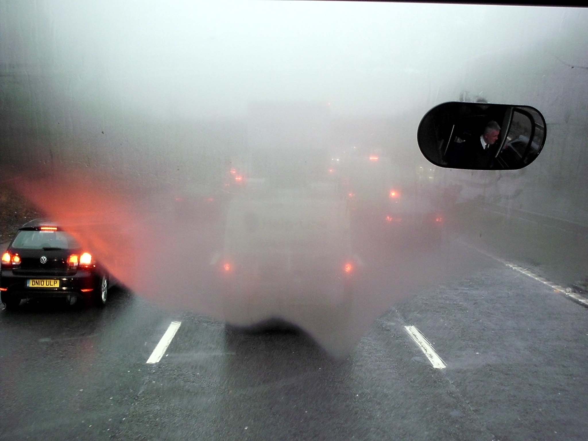 two cars on road with fog and mist covering the area