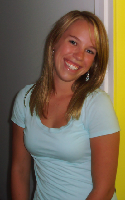 a woman smiling and wearing a light blue shirt