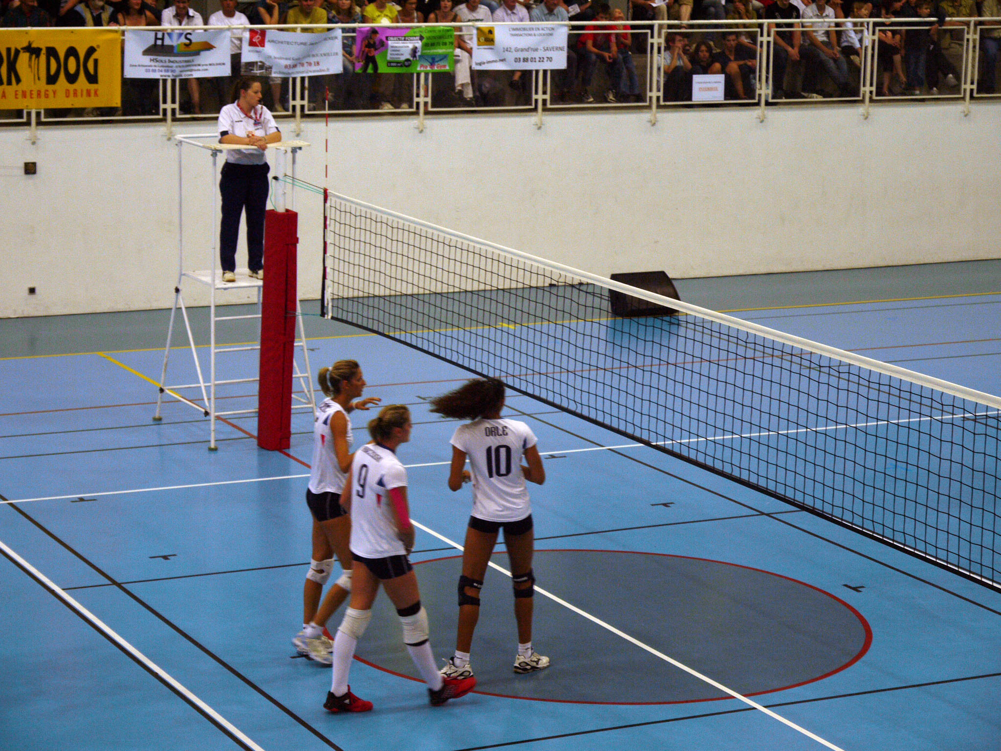 four players from different countries standing on a tennis court and talking