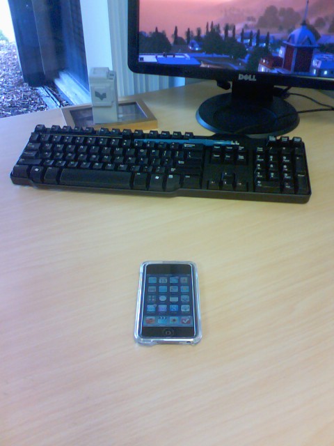 a cell phone next to a keyboard on a desk