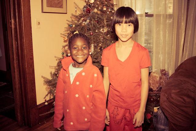 two children standing next to each other in front of a christmas tree