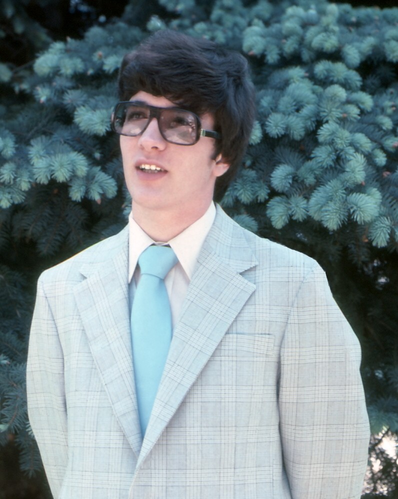 a man wearing a jacket, tie and glasses