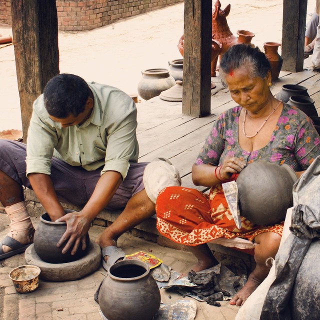 two people sitting on the ground by pots