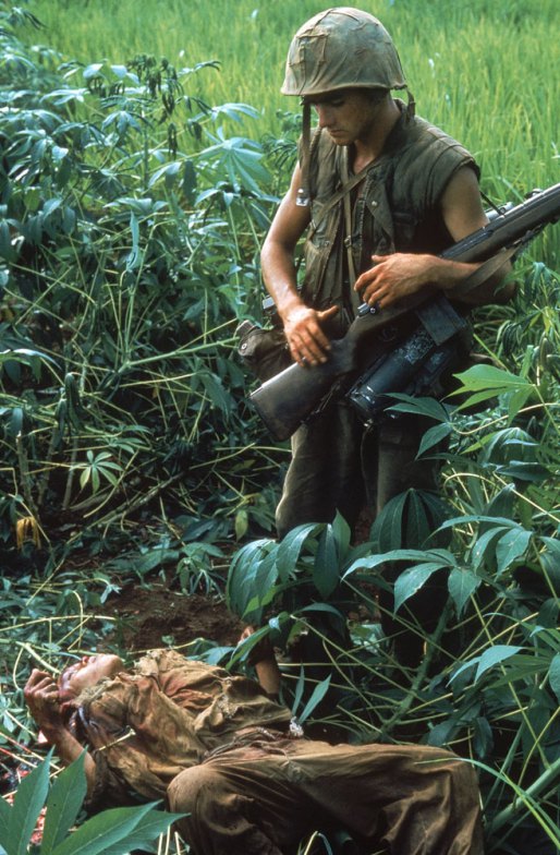 soldier carrying rifle in jungle looking at another man