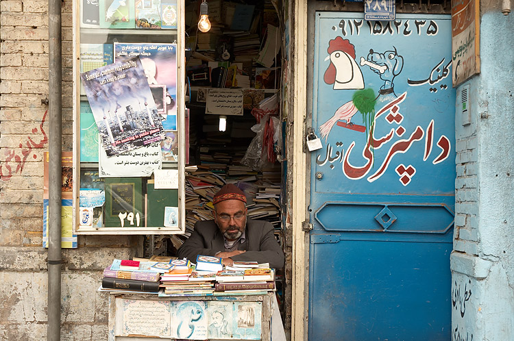 man reading in doorway to the store which sells newspapers