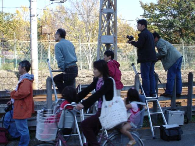 many people are hing luggage by the railroad tracks