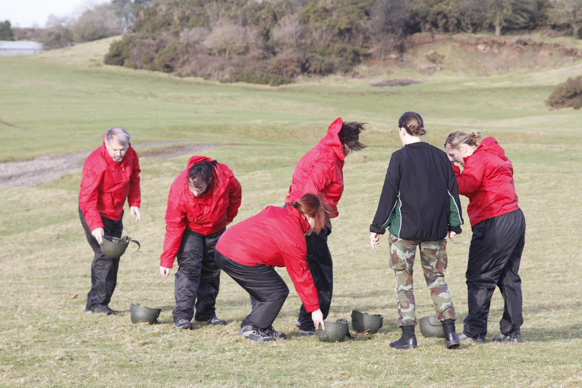 seven people in red coats, all playing with toy blocks