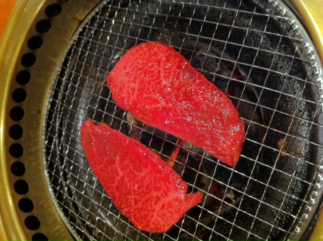 a black grill with a red meat on it
