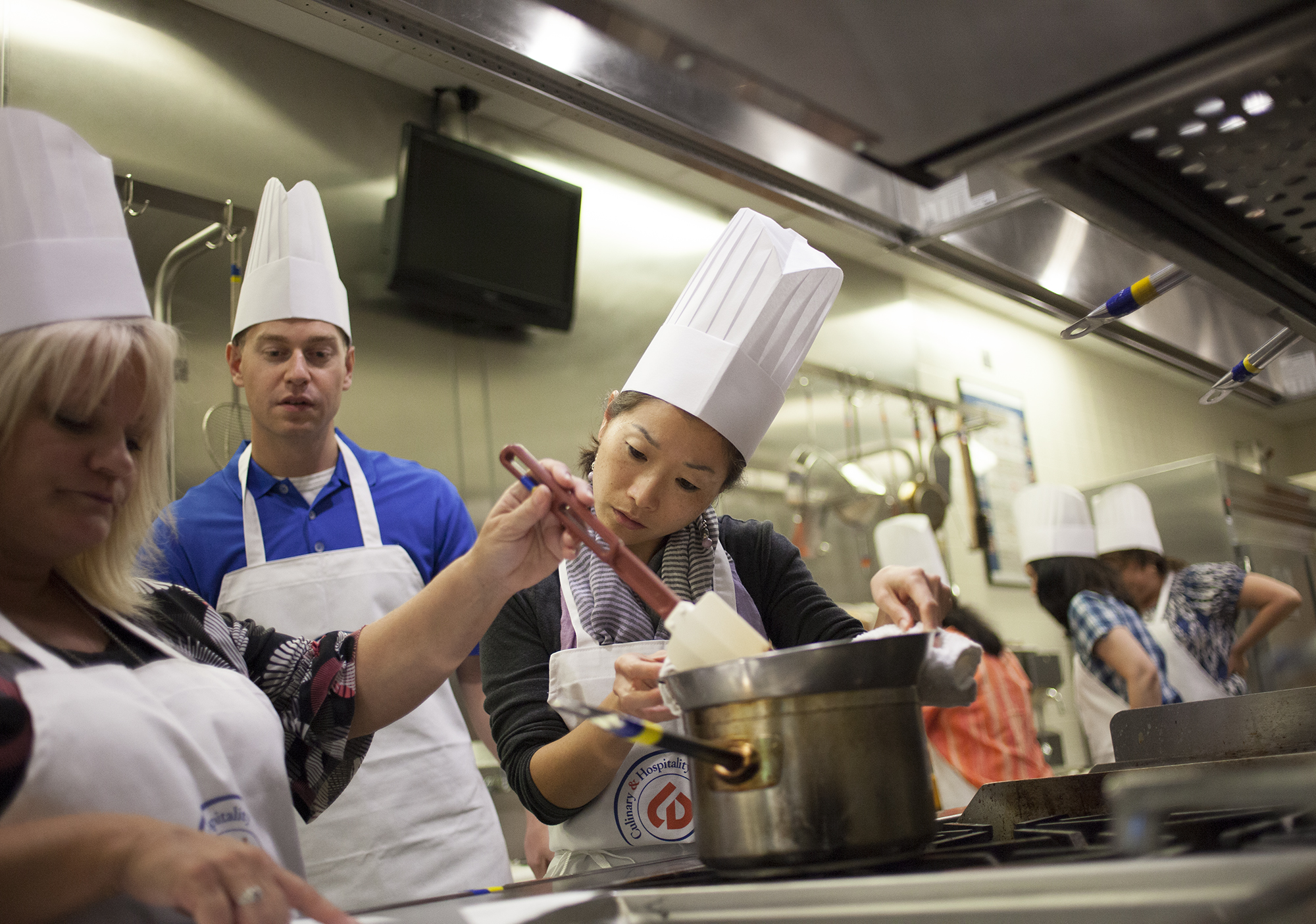 three people in aprons and hats preparing food